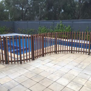steel and wood fence snaking its way around a pool installation 